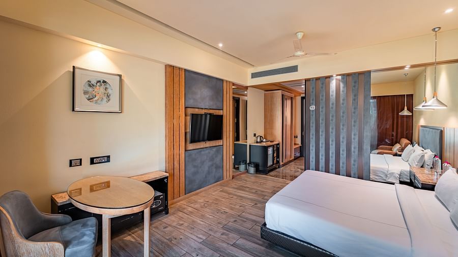 Club Room features a spacious bed, a round study table with a chair, a wall-mounted television, and an air conditioner fixed to the side at Crescent Spa & Resort, Indore