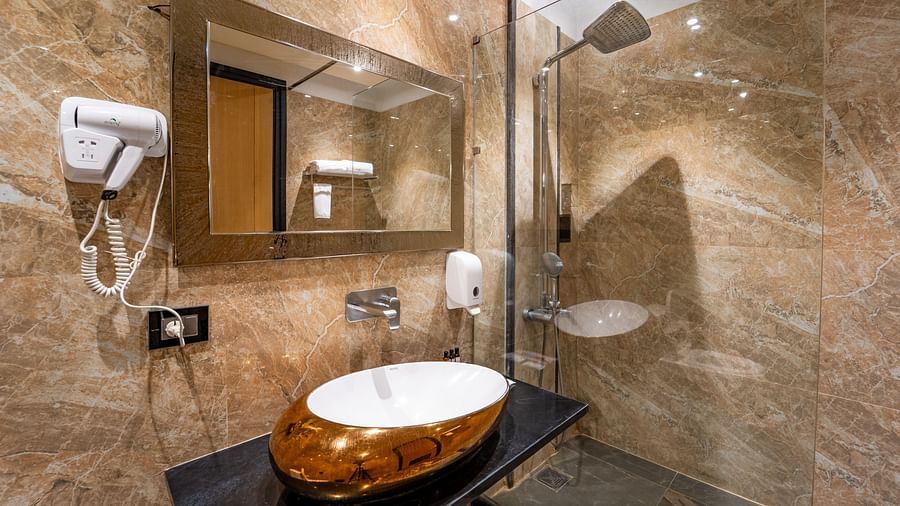 Club Room bathroom features a wall-mounted hand wash and hairdryer, a horizontally placed mirror above the wash basin, and bright lighting at Crescent Spa & Resort, Indore