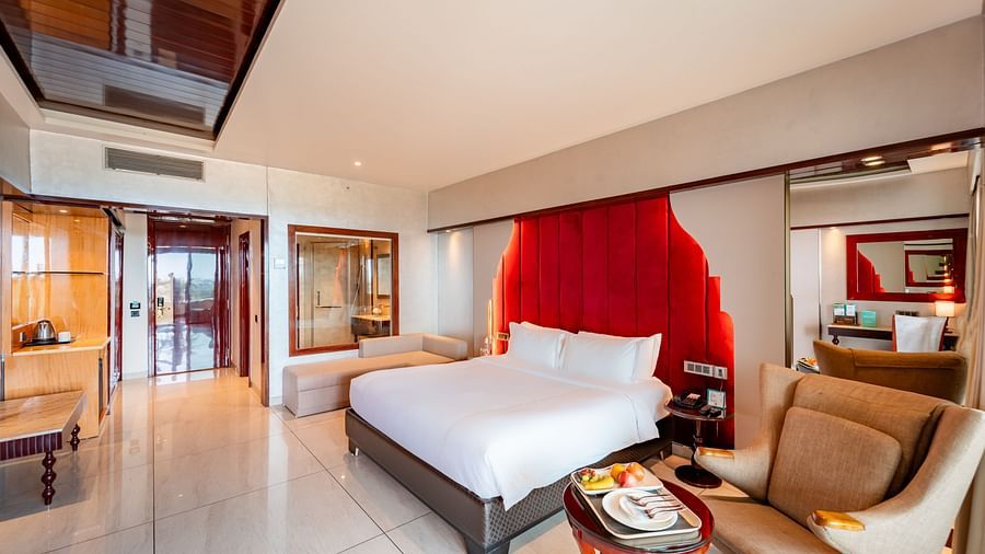 Executive Room features a spacious bed, a one-seater sofa with a round table and snacks, and a doorway leading to the exit at Crescent Spa & Resort, Indore.