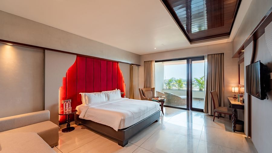 Executive Room features a spacious bed, cushioned sofa, wall-mounted television, and a large doorway leading to the balcony at Crescent Spa & Resort, Indore