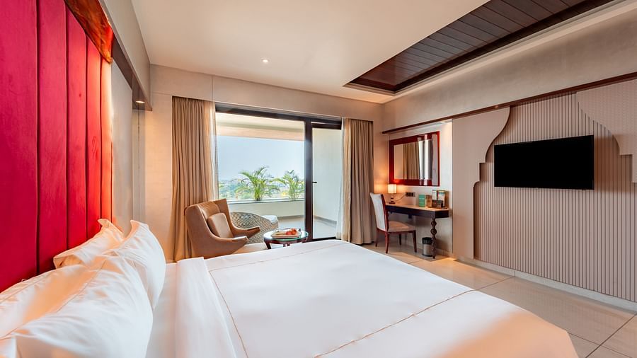 Executive Room features a spacious bed,  wall-mounted television, and a large window showcasing the balcony view at Crescent Spa & Resort, Indore