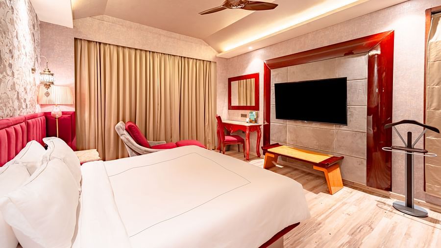 Executive Suite features a spacious bed, a wall-mounted television opposite it, and curtains covering the window at Crescent Spa & Resort, Indore