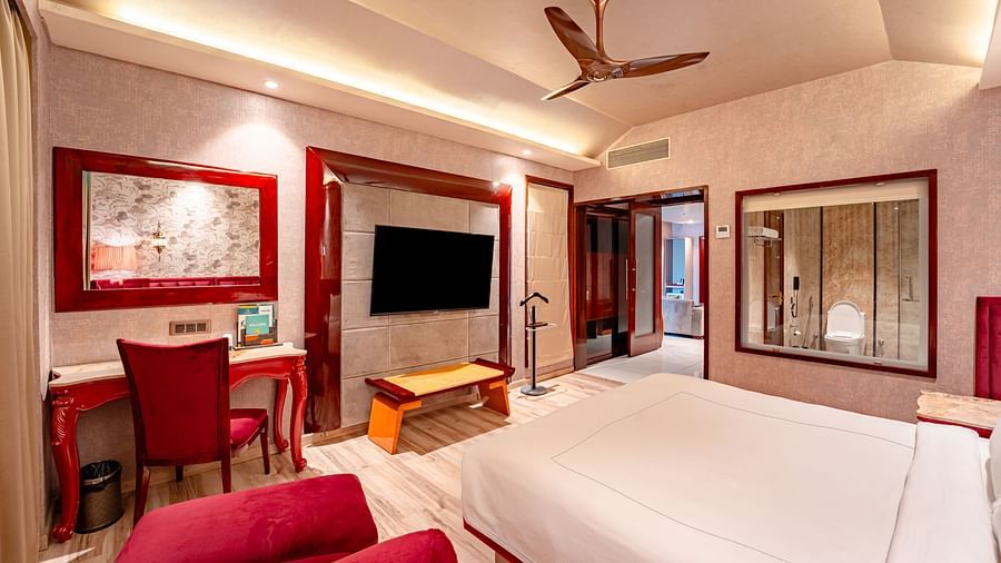 Executive Suite features a spacious bed with a bedside table, warm lighting, and a pathway leading to the next room at Crescent Spa & Resort, Indore