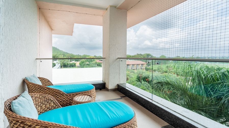 Two oval cushioned chairs are positioned on the balcony for enjoying the view at Crescent Spa & Resort, Indore