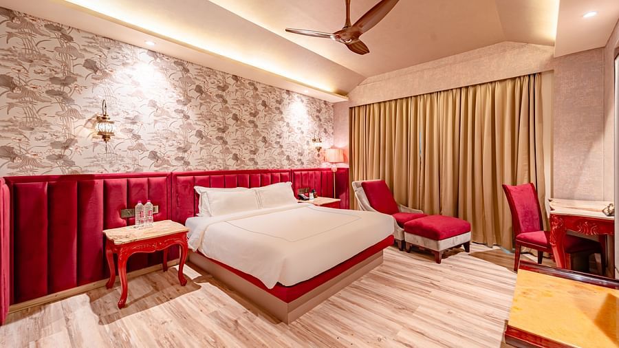 Executive Suite features a spacious bed, a bedside table, and cushioned furniture next to the curtain-covered windows at Crescent Spa & Resort, Indore