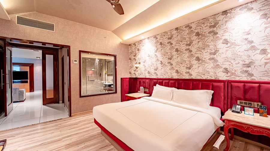 Executive Suite features a spacious bed with a bedside table, warm lighting, and a pathway leading to the next room at Crescent Spa & Resort, Indore
