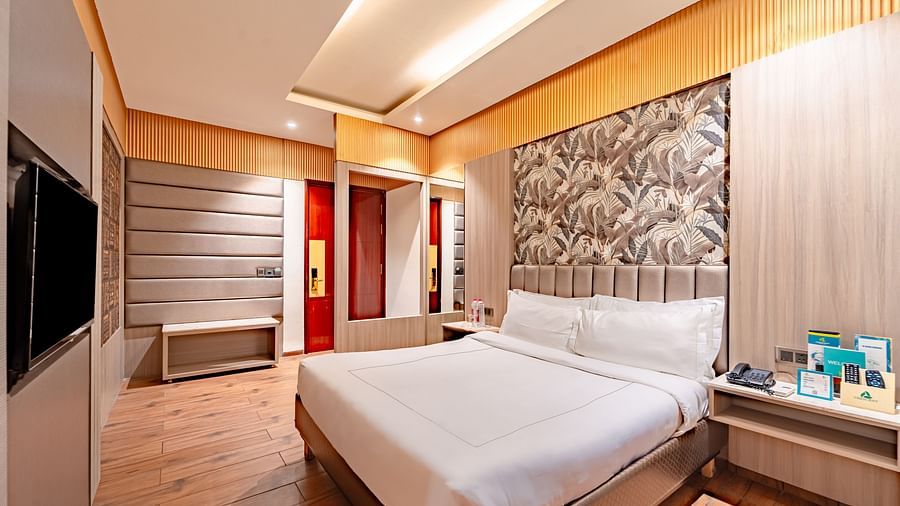Family Room offers a spacious bed with a bedside table, window curtains, and a wall-mounted television at Crescent Spa & Resort, Indore