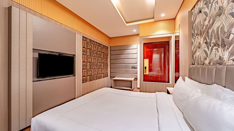Family Room offers a spacious bed with a bedside table, window curtains, and a wall-mounted television at Crescent Spa & Resort, Indore