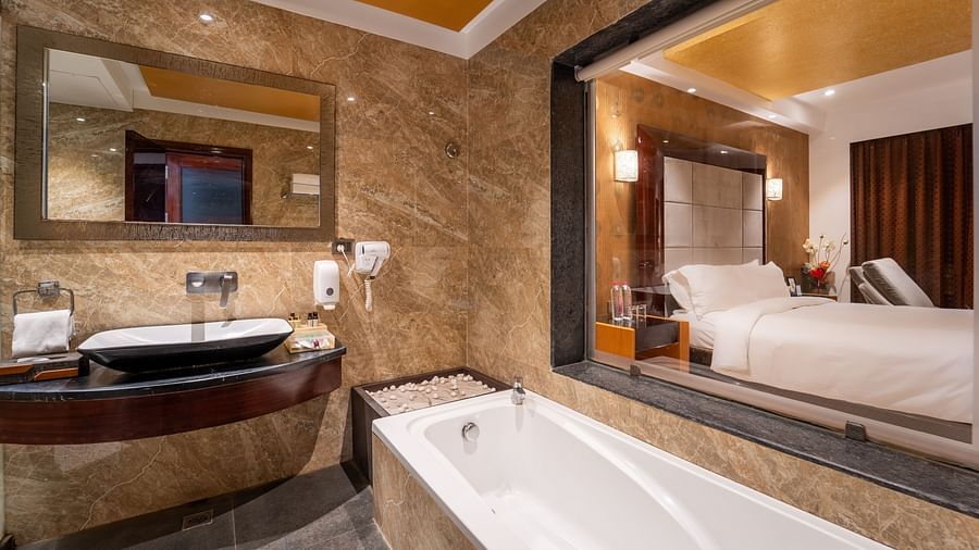 The Family Suite bathroom at Crescent Spa & Resort, Indore, features a bathtub and a washbasin with a mirror above.