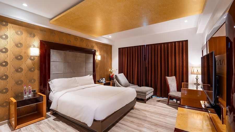 Family Suite includes a spacious bed with a bedside table, large windows with curtains, and a wall-mounted television at Crescent Spa & Resort, Indore