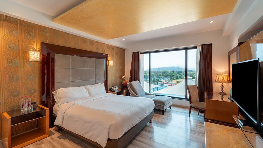 Family Suite includes a spacious bed with a bedside table, large windows, and a wall-mounted television at Crescent Spa & Resort, Indore
