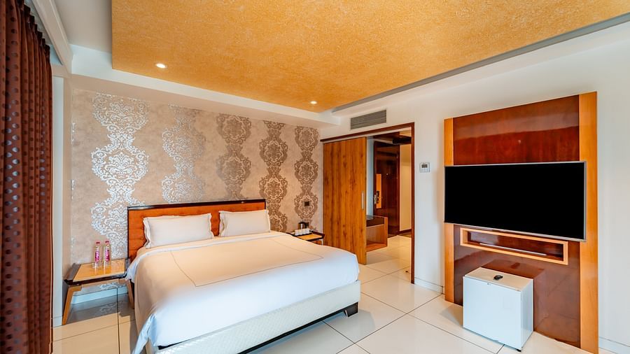 Family Suite featuring a spacious bed with bedside tables on both sides and a wall-mounted television to the side at Crescent Spa & Resort, Indore