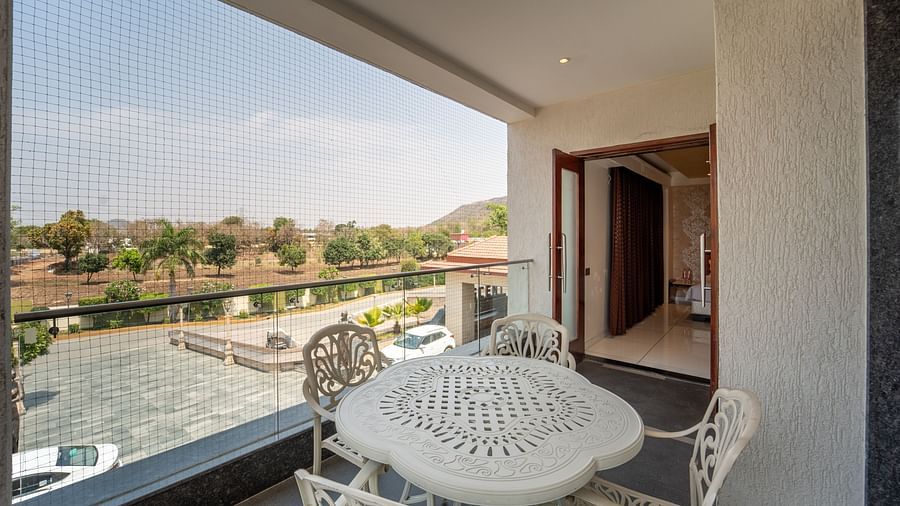 Family Suite balcony features a flower-shaped table with chairs around it, perfect for enjoying the view at Crescent Spa & Resort, Indore