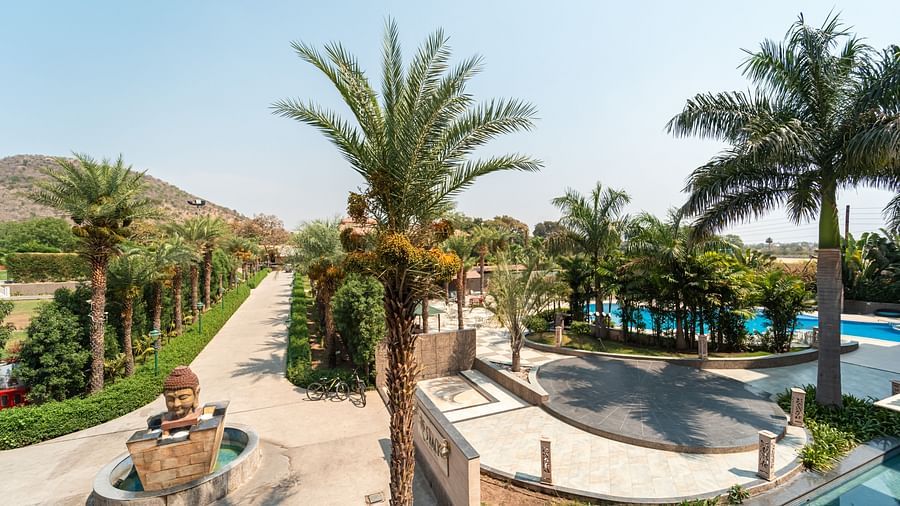 The picturesque walking path beside the pool at Crescent Spa & Resort, Indore, lined with lush greenery and serene views
