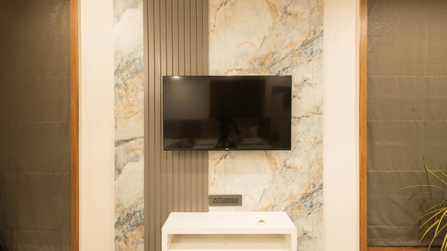 A focus shot on the flat-screen, wall mounted TV in the Daksh Bliss Room at Daksh Eden Greenz, Sasan Gir.