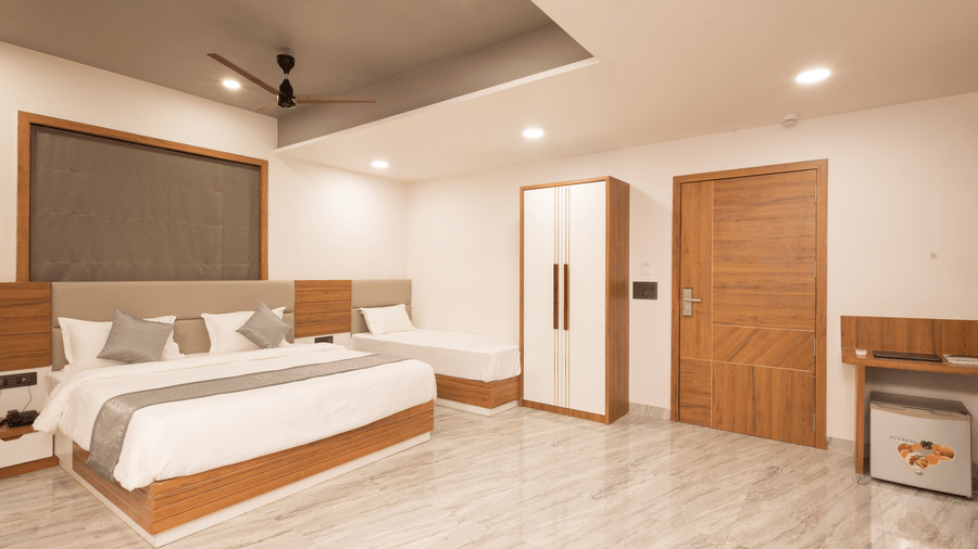 Wide view of the Daksh Pride room at Daksh Eden Greenz, Sasan Gir, showcasing its double, and single bed, wardrobe, and spacious layout.
