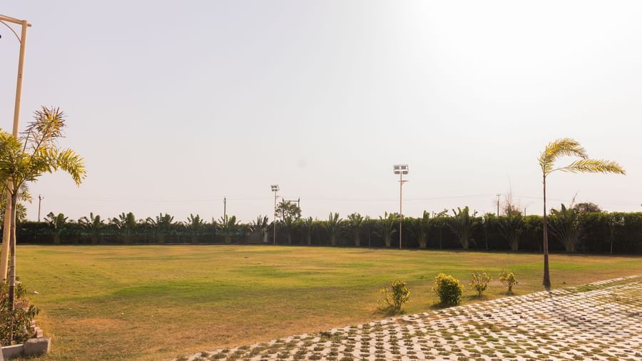 The expansive lawn at the Daksh Eden Greenz, Sasan Gir on a bright day.