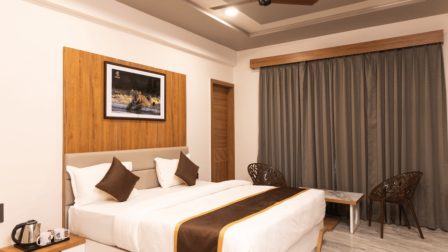 Highlighting the double bed situated in the centre of the Daksh Comfort Room at Daksh Eden Greenz, Sasan Gir.