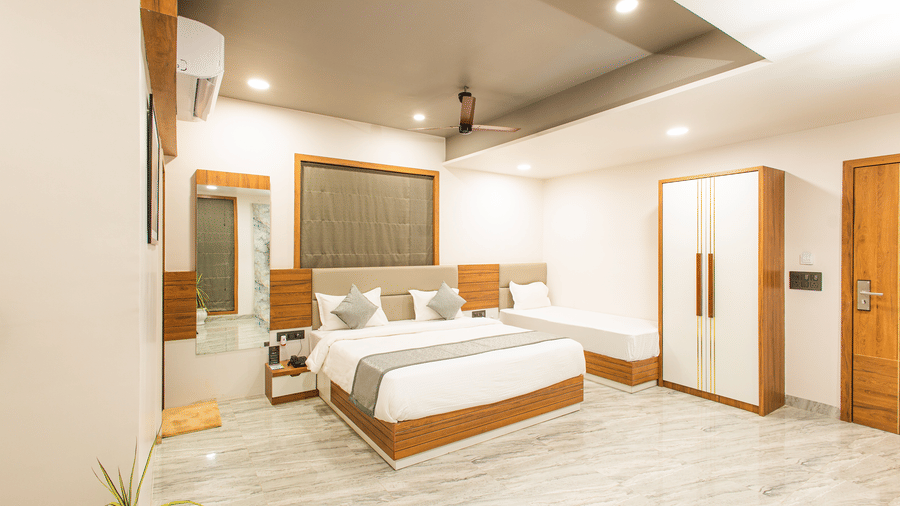 Wide view of the Daksh Pride room at Daksh Eden Greenz, Sasan Gir, showcasing its double, and single bed, wardrobe, and spacious layout.