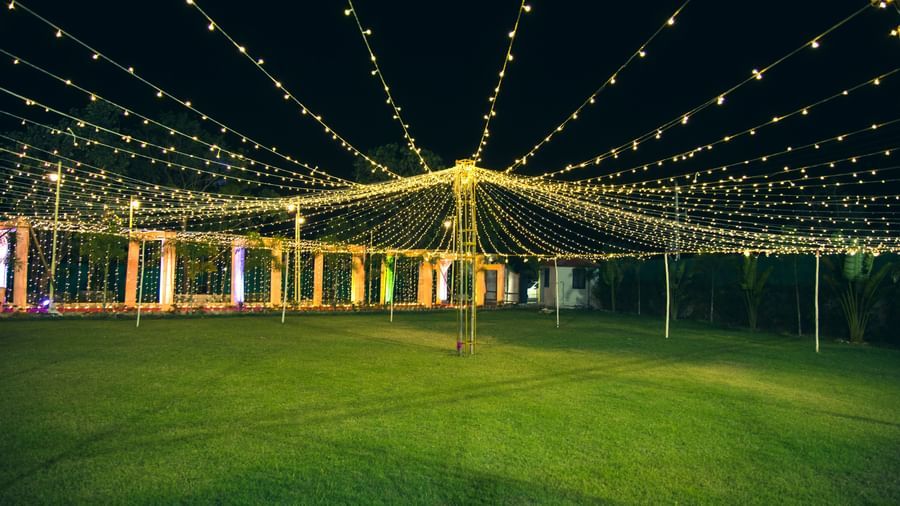 A wide view of lush lawn illuminated with hanging fairy lights arranged for an event at Daksh Resort and Amusement Park.