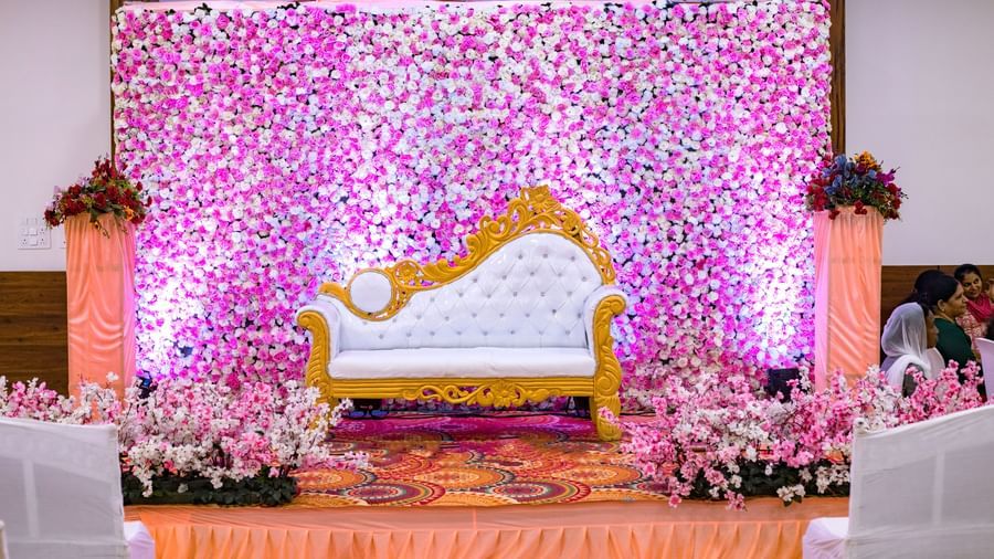 An upholstered sofa on an elevated stage decorated with flowers and ample lighting at Daksh Eden Greenz, Sasan Gir.