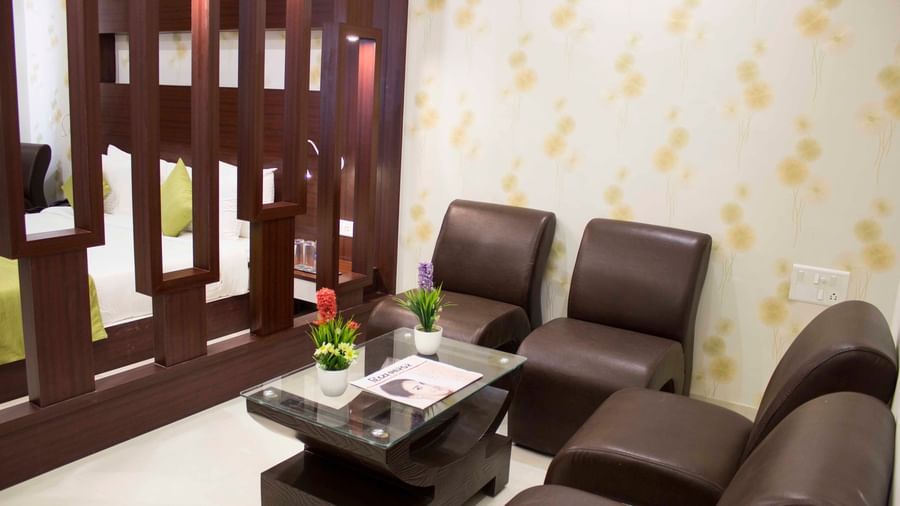 A luxurious hotel room with a bed, a partition, and a sofa seating area | Daksh Suite | Daksh The Madhuvan Suites