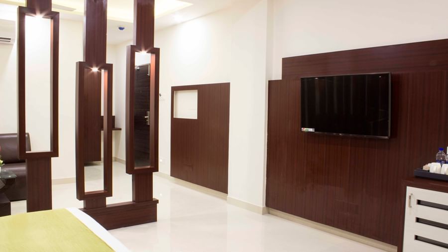A hotel room with a bed, flat-screen TV, and decorative wooden wall partitions | Daksh Suite | Daksh The Madhuvan Suites