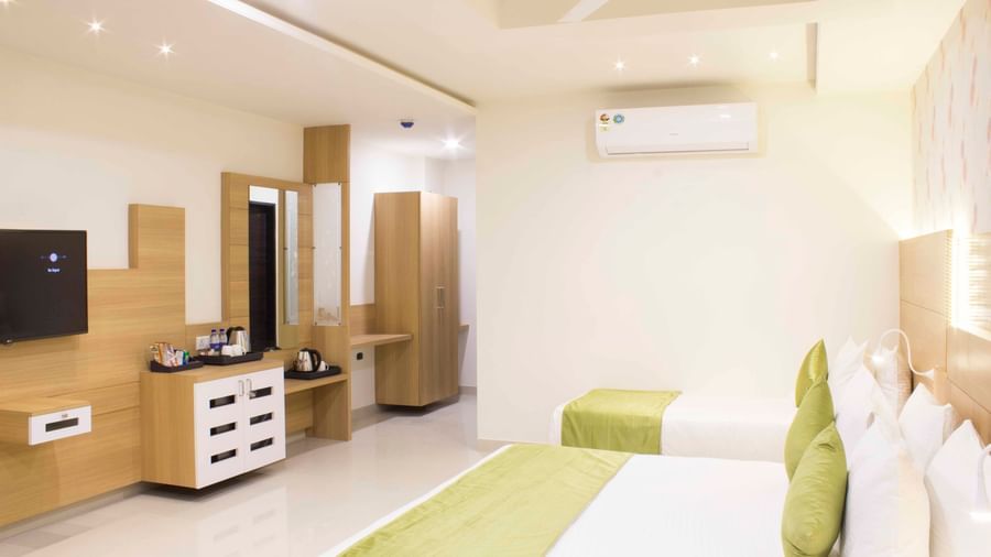 A hotel bedroom with a large bed, a single bed, with low headboards and a wall-mounted television | Daksh Pride Room | Daksh The Madhuvan Suites