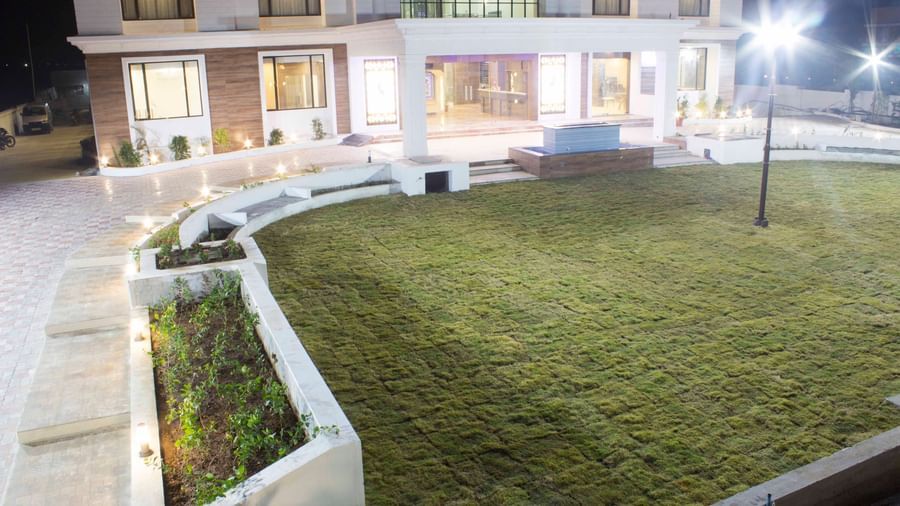 A hotel's exterior at night, showcasing its illuminated architecture and surrounding gardens | Daksh The Madhuvan Suites