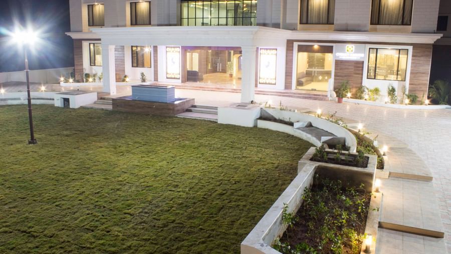 A hotel's exterior at night, showcasing its illuminated architecture and surrounding gardens | Daksh The Madhuvan Suites