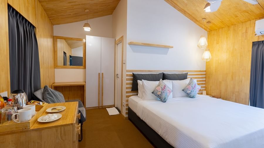 corner view image of the premium room featuring a plush bedding along with a corridor with a wardrobe at the far end - Darza Resorts