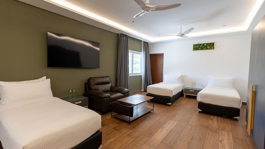 image featuring a bedroom with three separate single beds along with a wall mounted tv and a massage chair in the luxury group stay villa - Darza Resorts