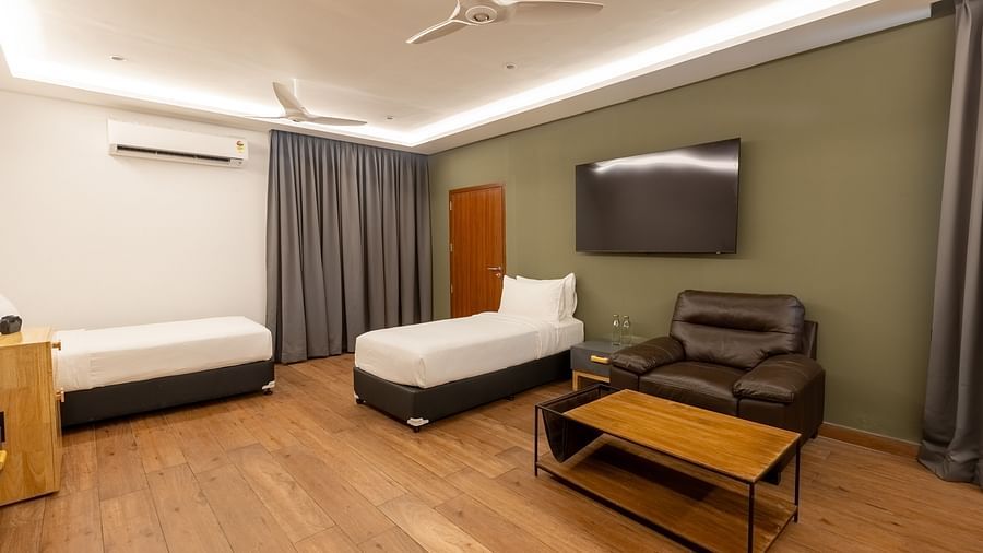 image of a bedroom featuring two single beds placed opposite to each other and a comfortable arm chair at the luxury group stay villa - Darza Resorts