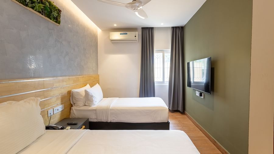 side view of a bedroom featuring a set of twin beds with a wall mounted television at the luxury group stay villa - Darza Resorts