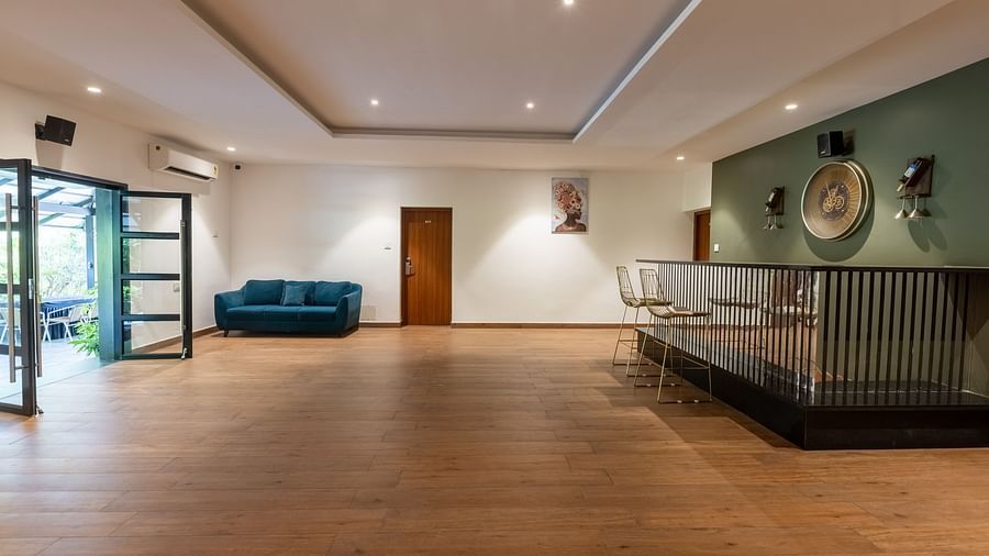 image of the expansive living room with a teal coloured couch in the corner and a standing bar at the luxury group stay villa - Darza Resorts