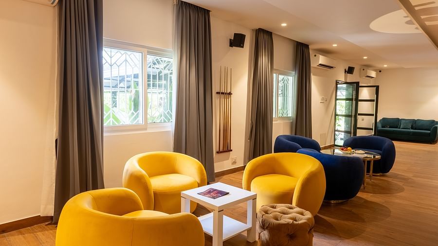 image of the common seating area with huge cushioned yellow chairs with boar games at the luxury group stay villa - Darza Resorts
