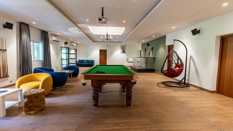 image of the entire living room of the luxury group stay villa featuring a huge pool table along with cushioned seats besides it - Darza Resorts