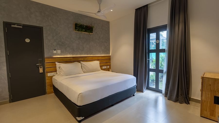 image of a bedroom featuring a plush double bed along with a door to outside at the luxury group stay villa - Darza Resorts