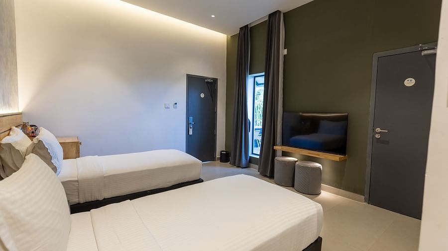 image of a bedroom of the luxury group stay villa featuring a tv placed right opposite tot he twin beds - Darza Resorts