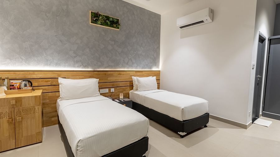 side view image of a bedroom featuring a twin bed and a wall mounted spit ac in a modern bedroom at the luxury group stay villa - Darza Resorts