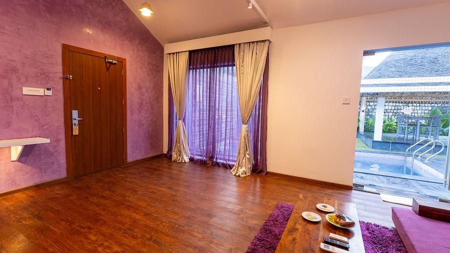 corner view image of the living room of the luxury villa with a huge french window at the end of the room opening to the outdoor seating area - Darza Resorts