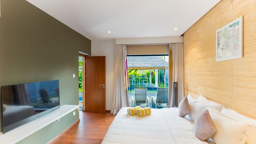 A room at Darza Resort featuring a double size bed, a flat TV screen, and a window where the chairs are placed in a garden.