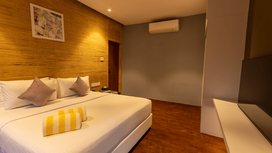 A contemporary bedroom at Darza Resorts features a neatly made bed, warm wooden flooring and soft lighting.