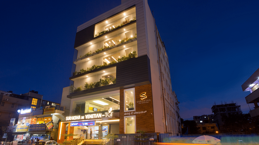 An exterior view of a modern multi-story building illuminated at dusk with signage and street activity - De Venetian by TGI, Brookefield