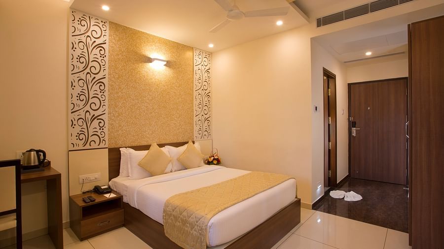 A hotel bedroom with a plush bed, decorative wallpaper and a view into the hallway - De Venetian by TGI, Brookefield