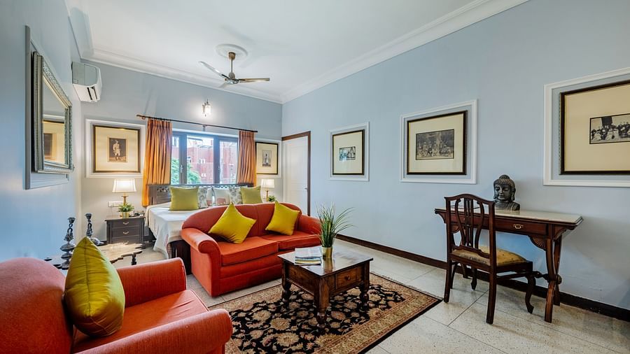 A well-lit suite at Dera Rawatsar in Jaipur offers comfortable seating, a wooden desk, framed artwork, and a glimpse into the sleeping area.
