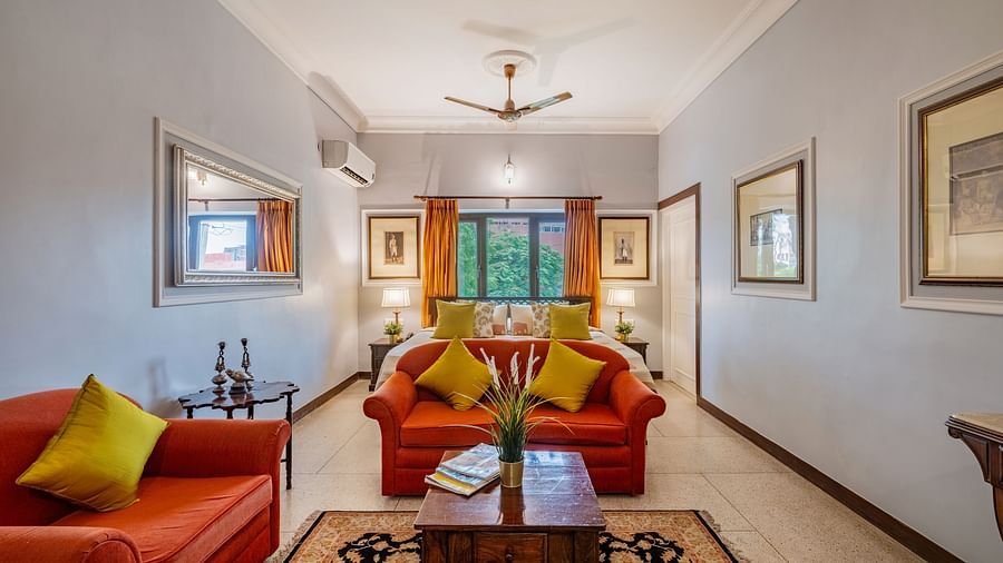 A spacious and elegant suite at Dera Rawatsar  in Jaipur offers comfortable seating areas, a wooden coffee table, and a glimpse of the inviting bed.