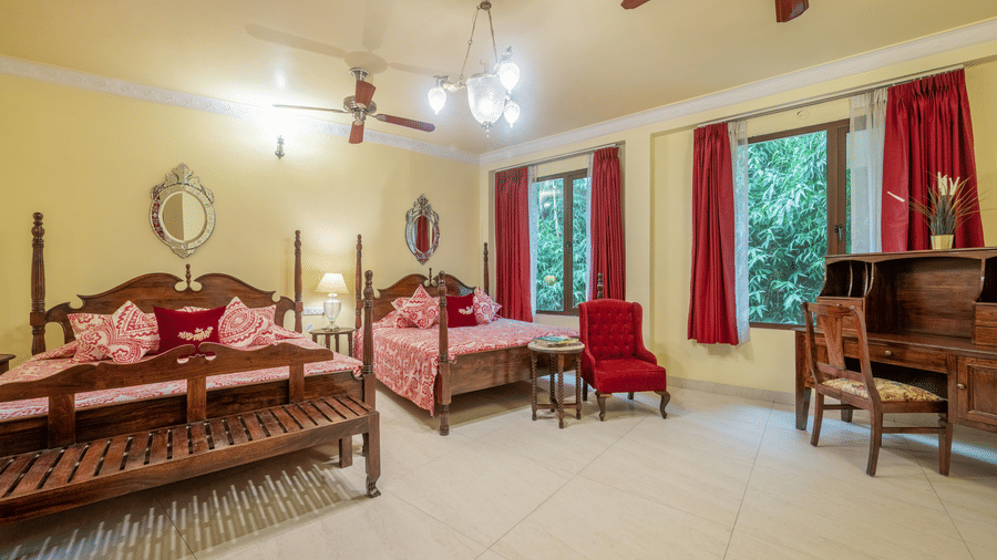 A spacious, well-lit bedroom featuring traditional wooden furniture, including two large four-poster beds with and bedding. 