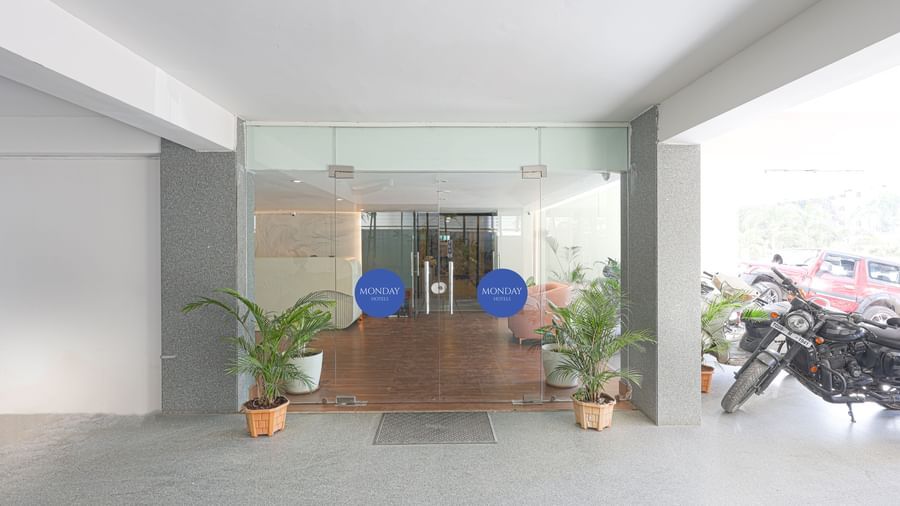 The entrance to Destino by Monday Hotels, Gachibowli, featuring transparent glass doors and potted plants.
