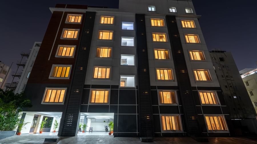 A low-angle shot of the illuminated facade of Destino by Monday Hotels, Gachibowli, at night, featuring its entrance.